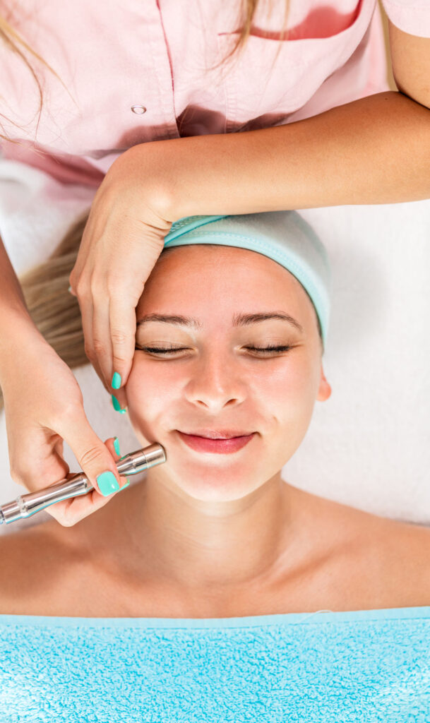 Beautician therapist applying face treatment in beauty salon to