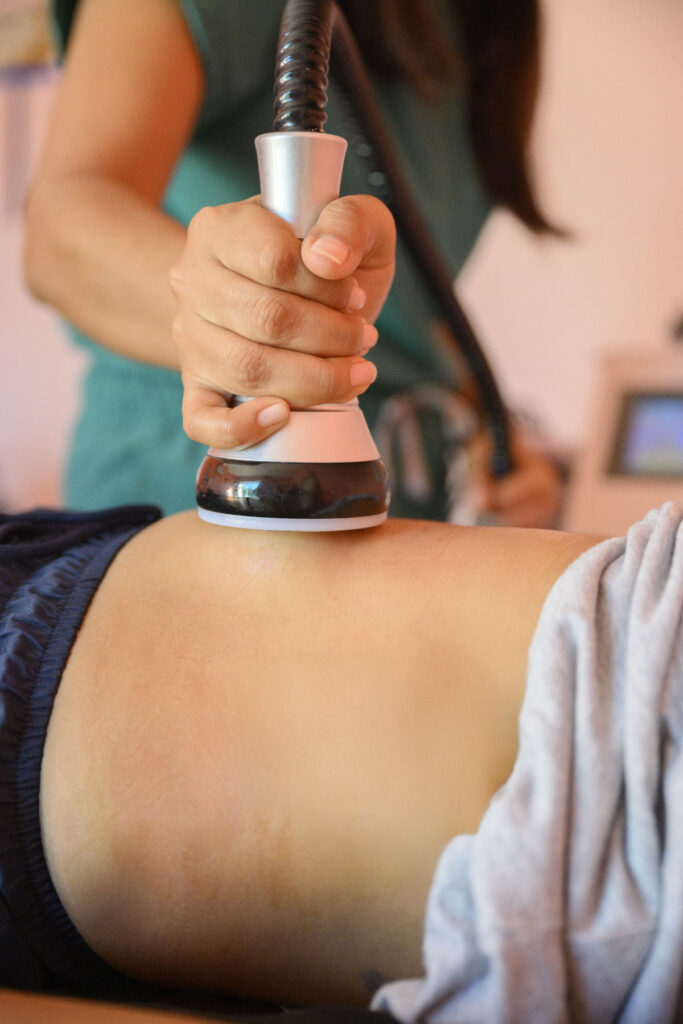 Beautician using cavitation machine on clients abdomen for body sculpting and fat reduction