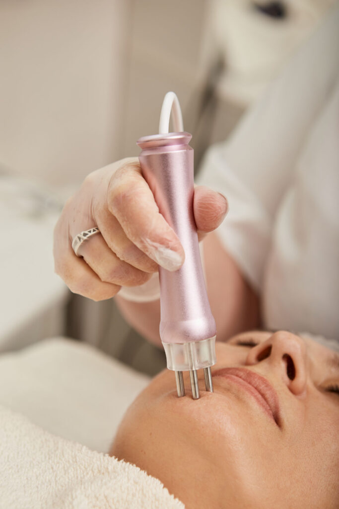 Middle aged woman receiving radiofrequency treatment in clinic